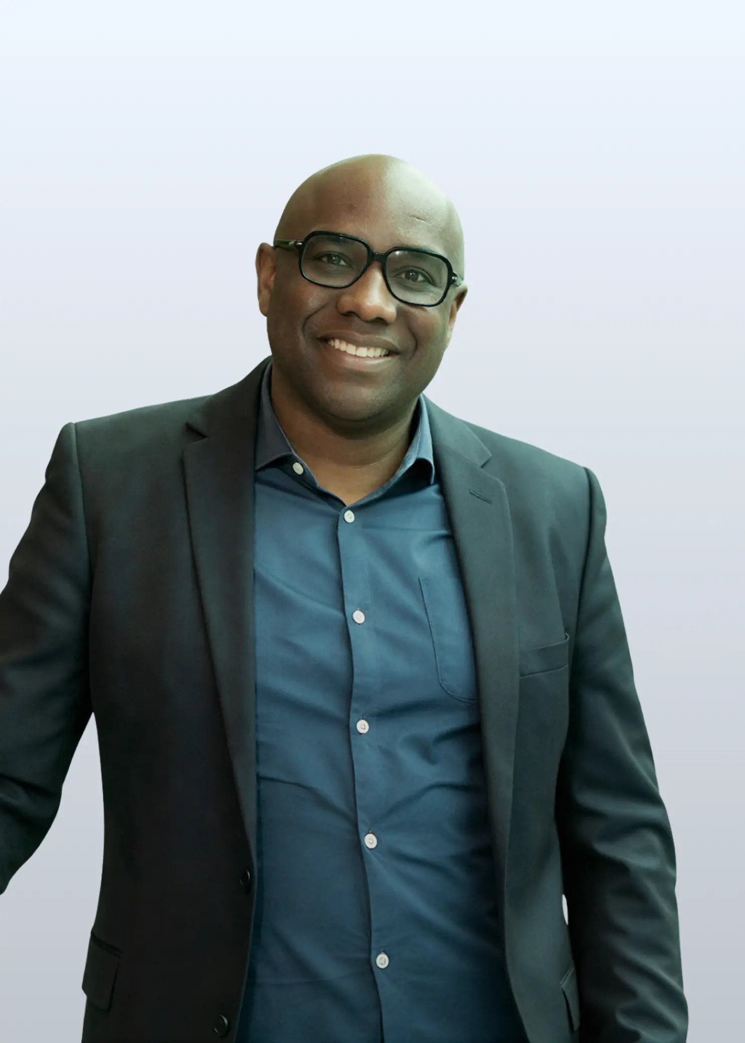 Foto van Otwien Vlieri op een witte achtergrond, lachend een arm leunend en de ander naast zijn lichaam.