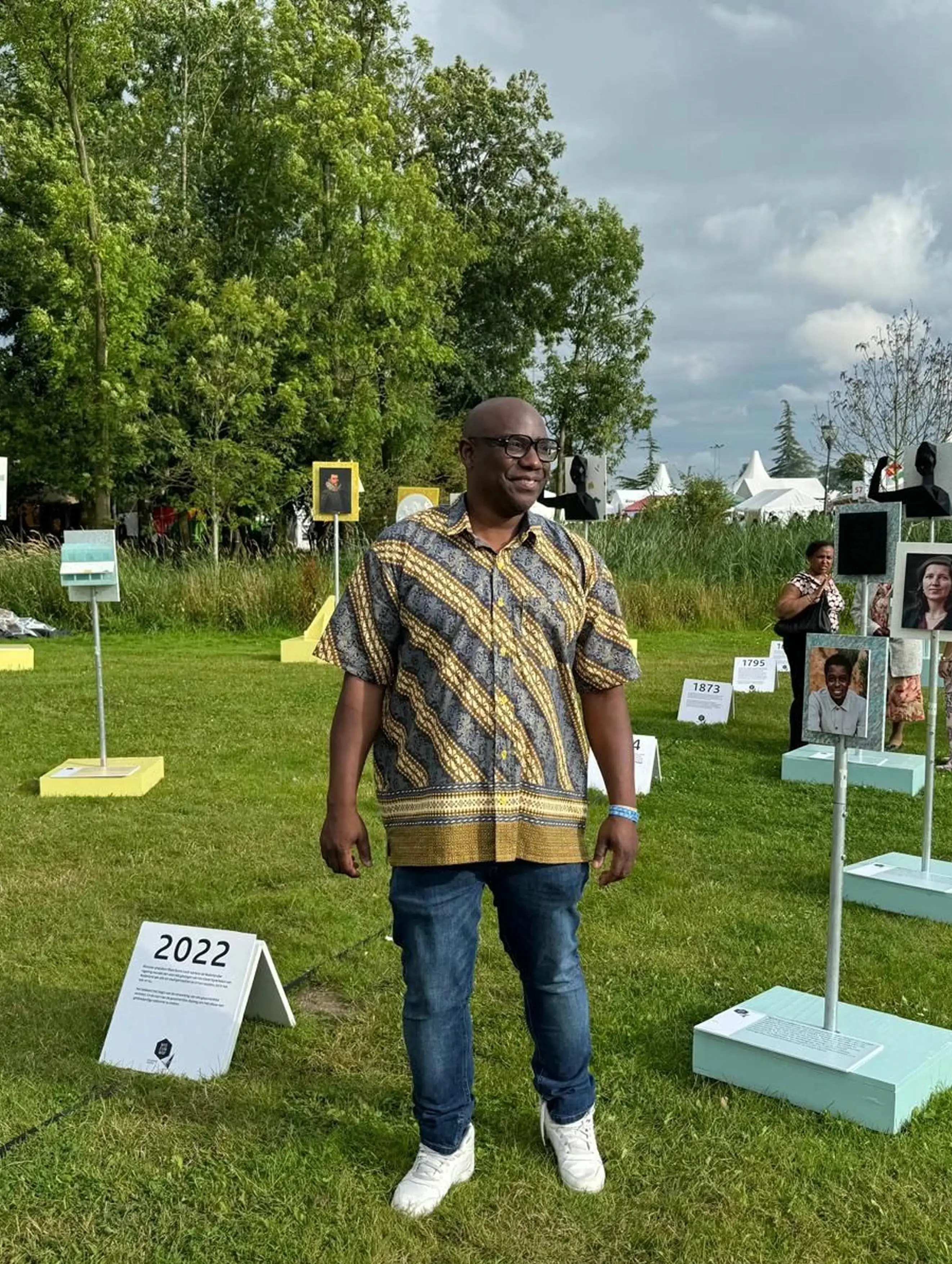 Foto van Otwien Vlieri op een witte achtergrond, lachend een arm leunend en de ander naast zijn lichaam.